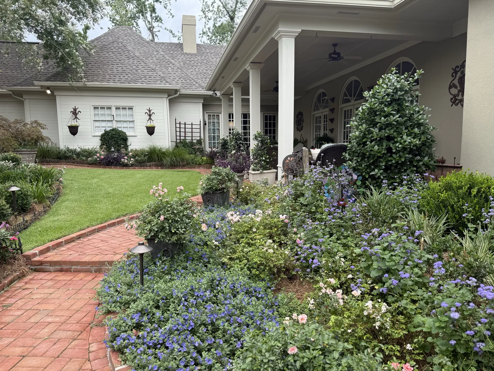 House porch with blue flowers and brick walkway